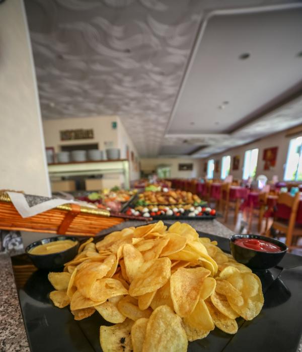 Patatine fritte su un piatto nero con salse in un ristorante elegante.