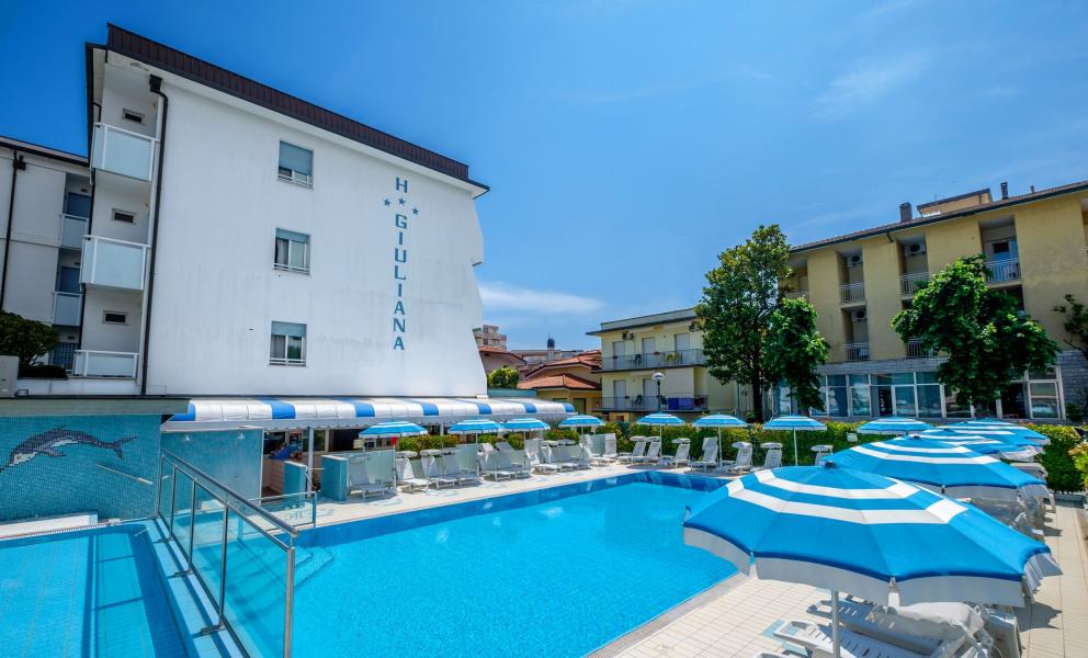 Piscina all'aperto con ombrelloni blu presso l'hotel Giuliana.