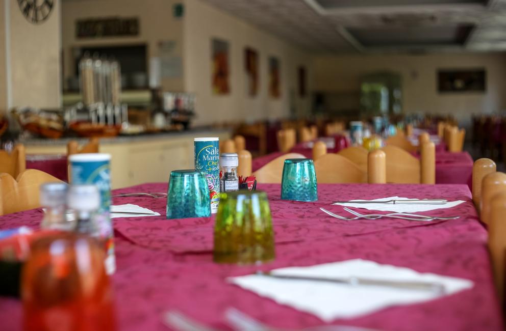 Tavoli apparecchiati con tovaglie rosse in un ristorante.