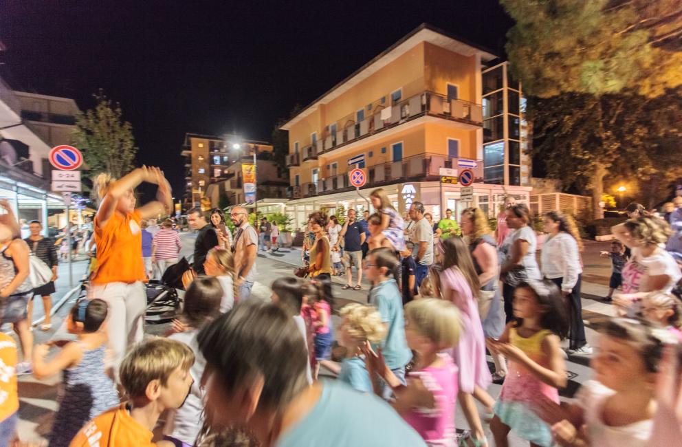 Folla di persone cammina per strada di notte in città.